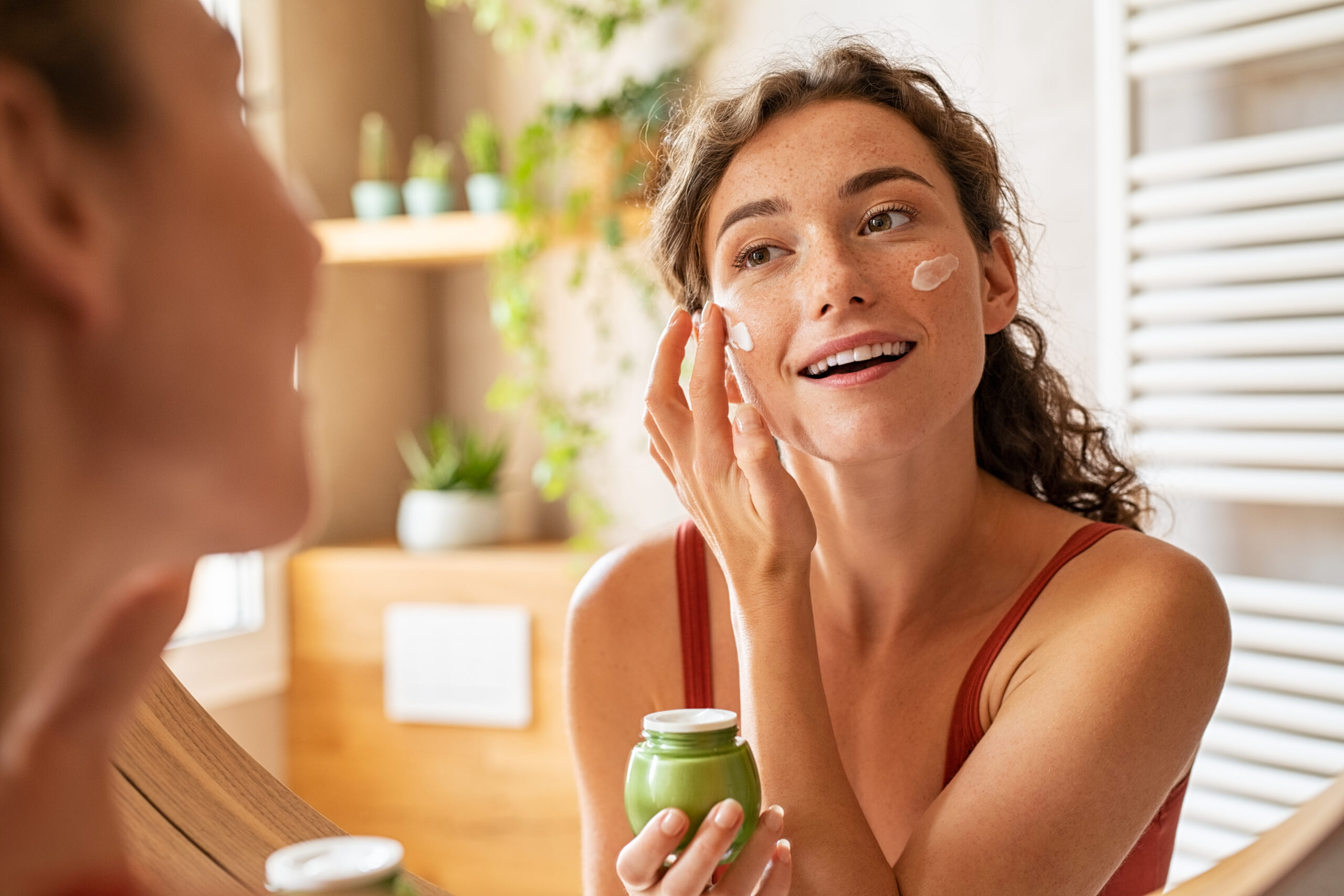 Portrait of senior and young woman Woman applying moisturiser on face during morning routine